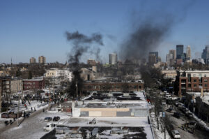 Federal immigration agents and community members confront each other at the Minneapolis shooting scene during a 2026 enforcement operation.