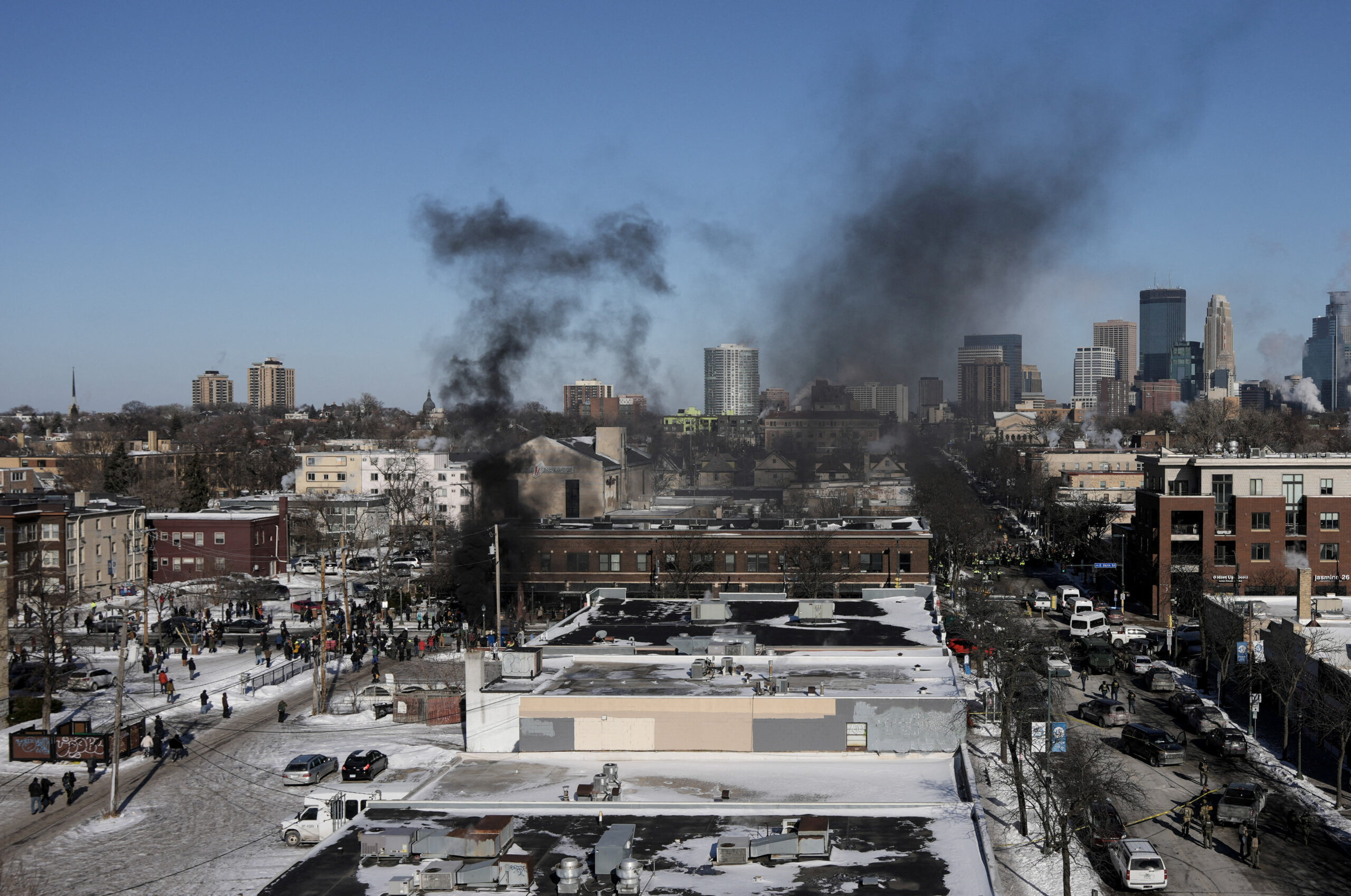 Federal immigration agents and community members confront each other at the Minneapolis shooting scene during a 2026 enforcement operation.
