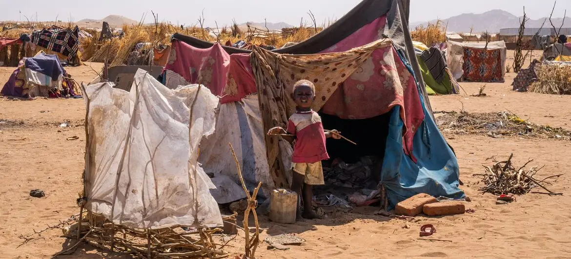 A child stands in front of a makeshift tent in a refugee camp in Tawila, North Darfur, following displacement due to ongoing conflict.